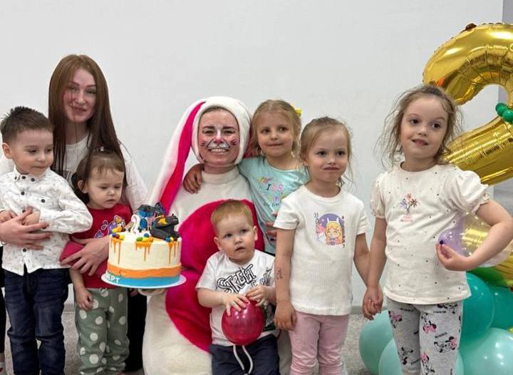 Аниматор в костюме и довольные праздником родители с детьми смеются и машут